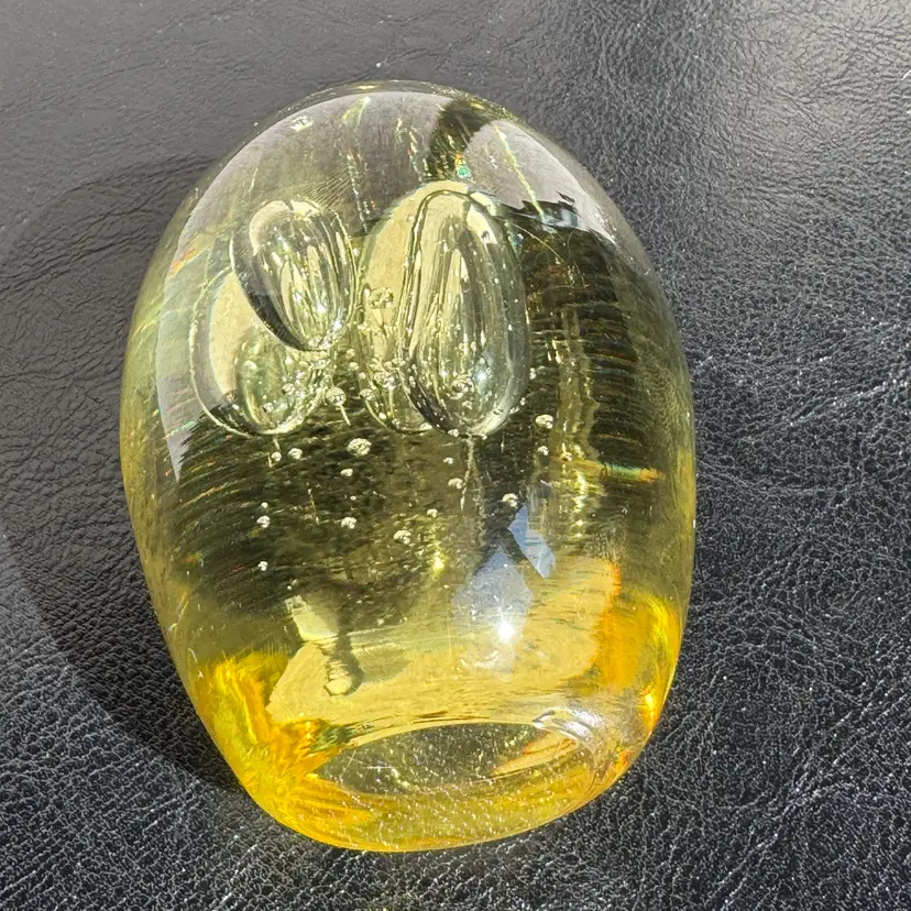 #0062 An unsigned vintage yellow art glass egg paperweight with internal bubbles.
