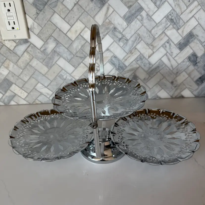 Vintage three-tier folding metal serving tray with filigree cutouts.