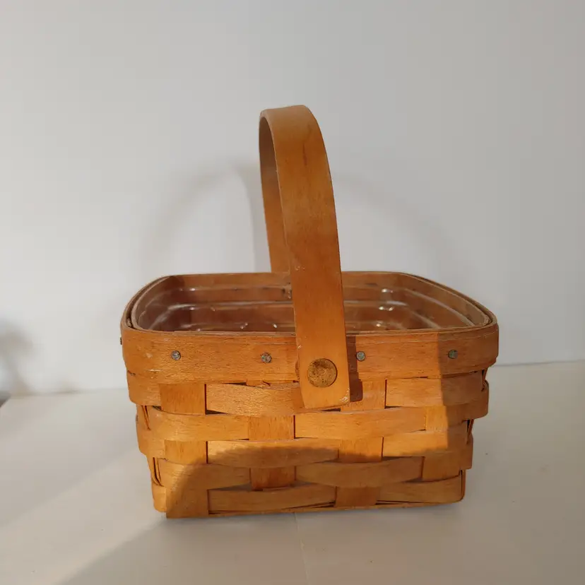Longaberger basket with plastic liner. Signed and dated. 7w x 3.5h x 7d. With handle 7.5 inches tall. Good condition.