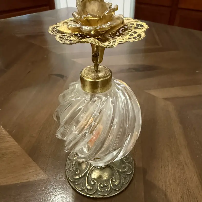 A Matson USA decorative perfume bottle with a glass body and ornate metal rose topper. 6”