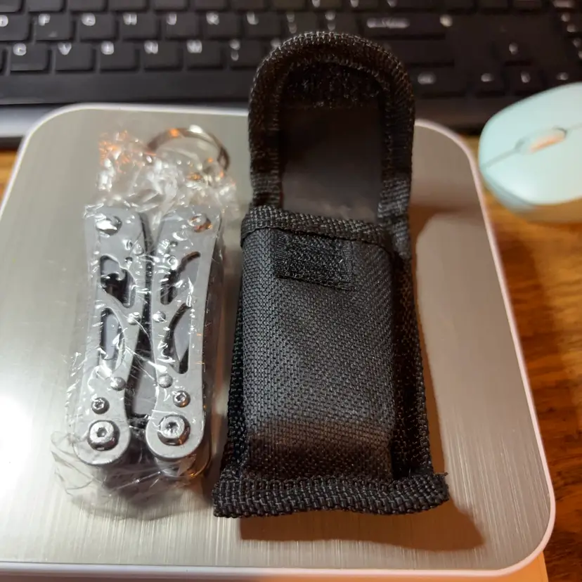 This item is a compact, stainless steel multitool featuring folding needle-nose pliers, a knife, and various screwdriver attachments.It includes a built-in keychain ring for portability, making it suitable for Everyday Carry (EDC) or outdoor activities like camping. Comes With A Case