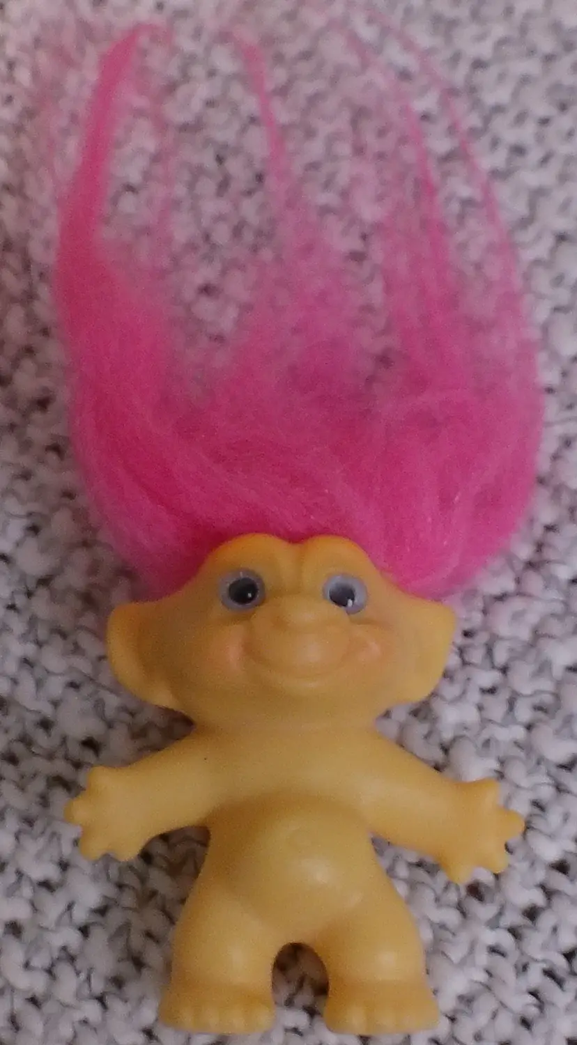 Vintage Russ troll doll featuring yellow plastic skin and tall, bright pink hair.