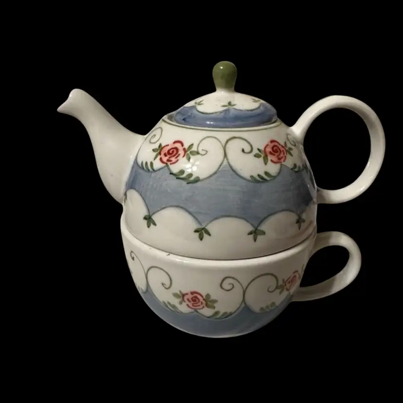 A modern ceramic teapot and cup set with hand-painted roses.