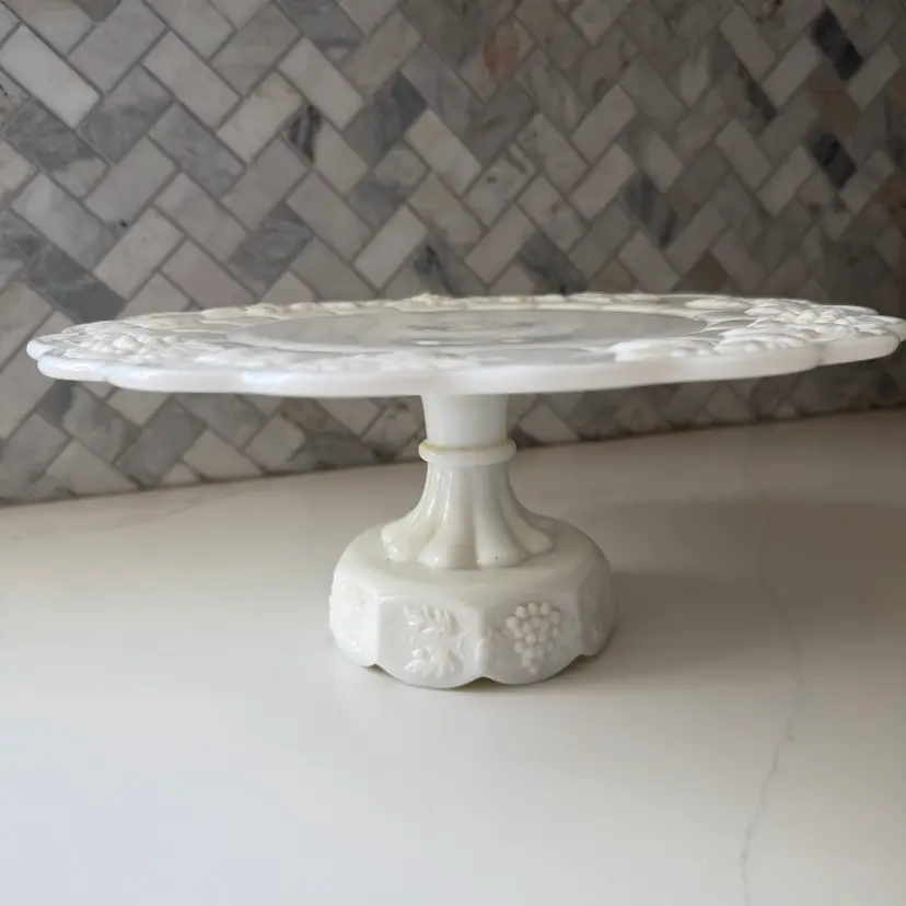 A vintage white milk glass paneled grape cake stand by Westmoreland. 5” Tall 10” Wide