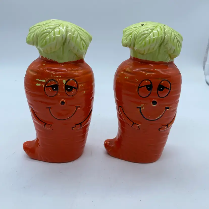 Vintage ceramic anthropomorphic carrot salt and pepper shakers with painted faces.