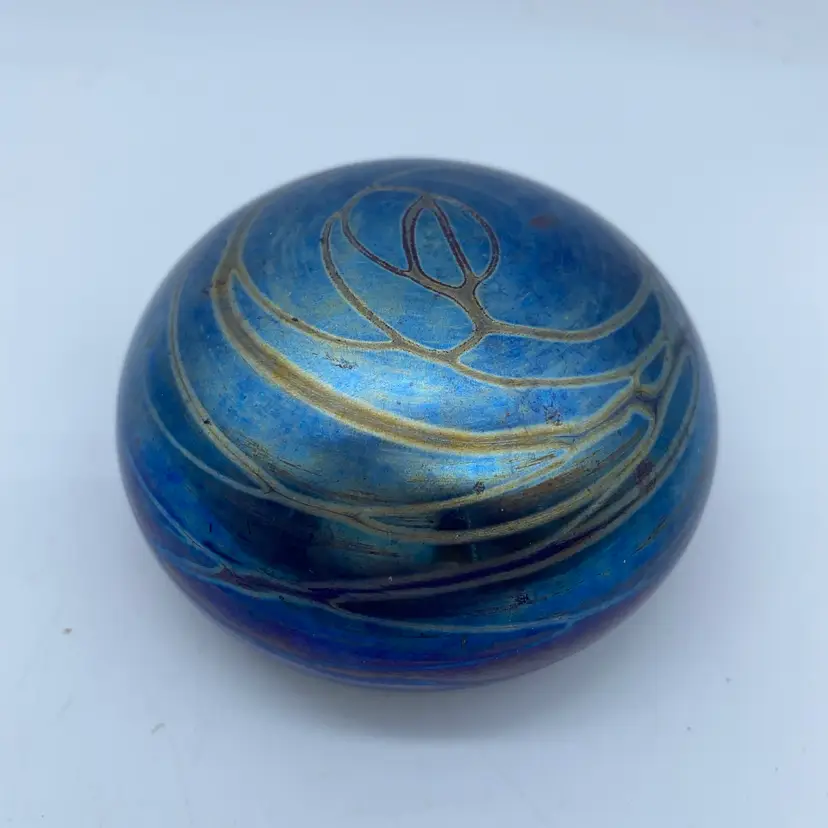 #0024 Iridescent blue art glass paperweight with golden linear trailing.