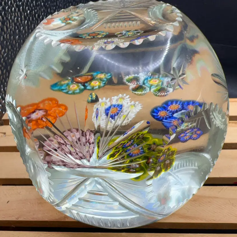 This is an antique French or Venetian art glass millefiori paperweight featuring multi-colored floral cane designs encased in clear glass with faceted or starburst-cut accents
