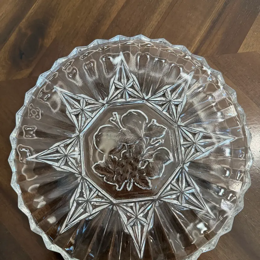 A vintage pressed clear glass plate with a fruit motif.