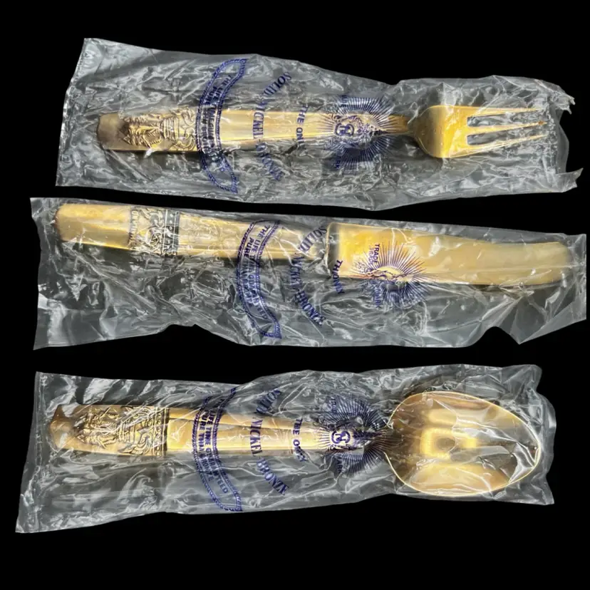 #2037A Beautiful Vintage Gold-Toned Small Flatware Set (a Fork, a Knife, and a Spoon) With The Erawan Motif (the Three-Headed Elephant) Embossed on the Handle. 
Sealed in Clear Plastic Wrappers Marked "Solid Nickel Bronze" and Originating from Thailand
In Original Presentation Box