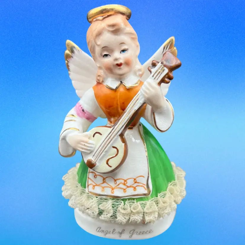 #182B Vintage Porcelain "Angel of Greece” Figurine. Angel Is Playing a Guitar Or Mandolin And Has Lace Trim On Her Dress 
Made In Japan By the ArtGift Corporation in 1958