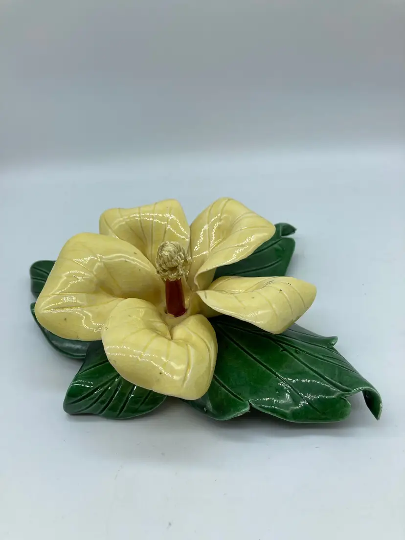 Vintage ceramic floral sculpture featuring a pale yellow blossom resting on glossy dark green leaves