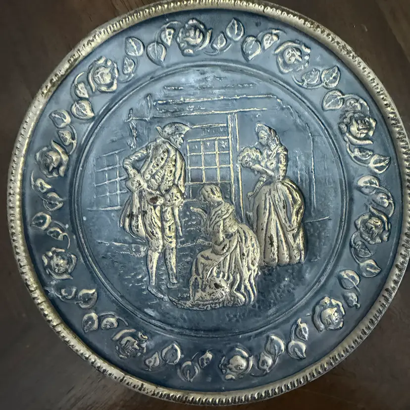 This is a mid-20th-century English embossed brass decorative wall plate.